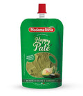 A green stand-up pouch of Artichoke olive paté with a red flip-top cap, shown on a plain white background. The front label features the brand name, product name, and a photo of olive paste with garlic and lemon.