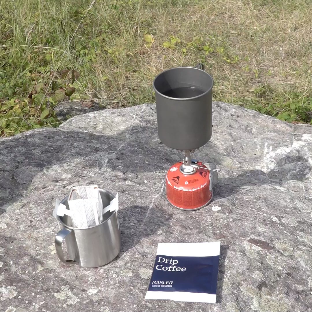 Preparing drip coffee outdoors with a stove.